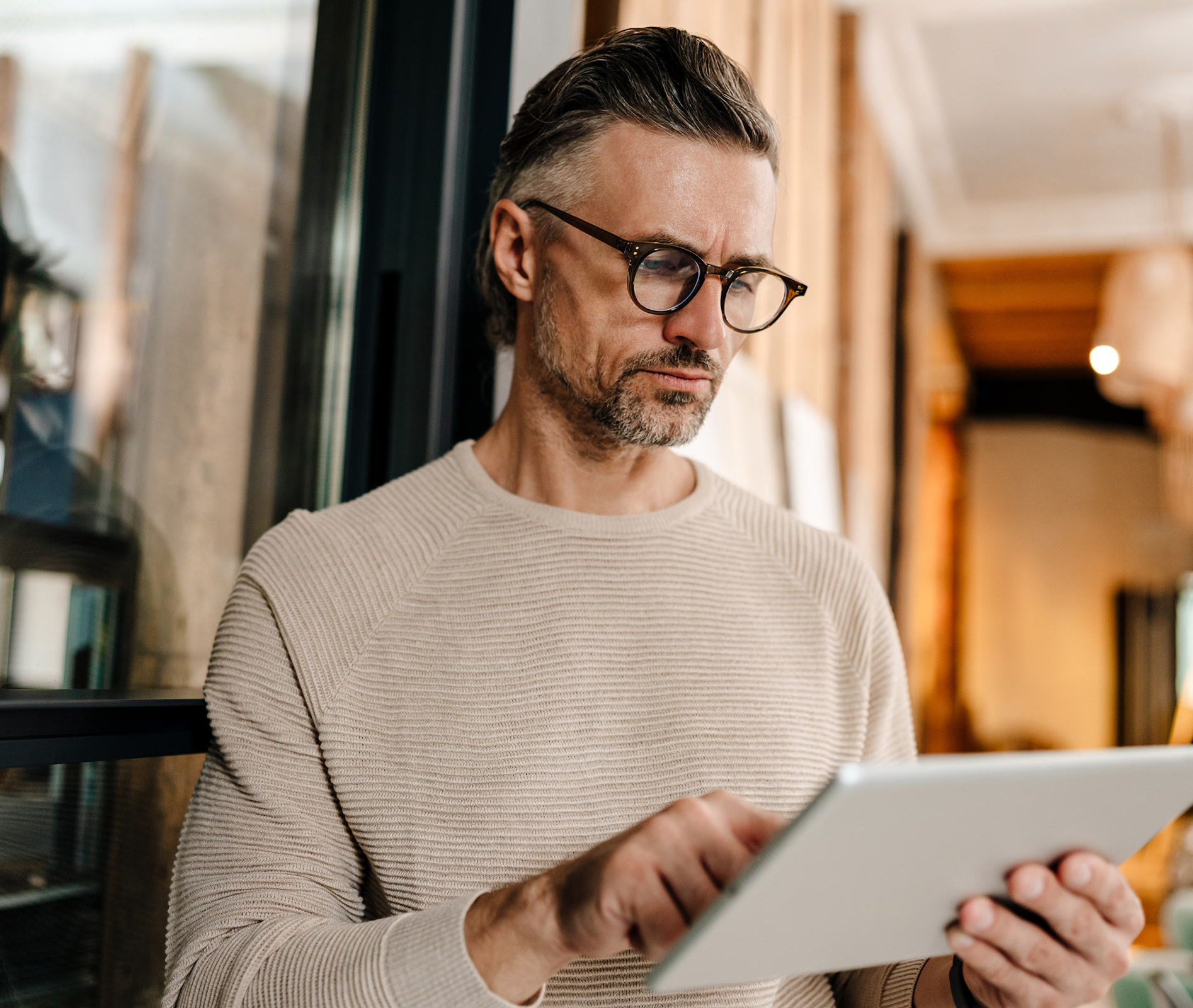Mann mit Tablet vor warmem Hintergrund.