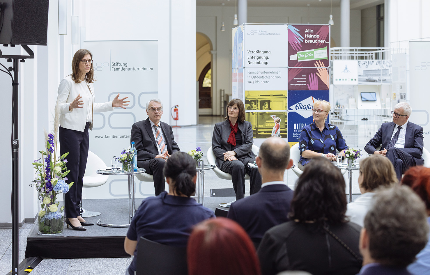 Frau steht auf einer Bühne vor einer Menschenmenge und hält einen Vortrag über Familienunternehmen in Ostdeutschland